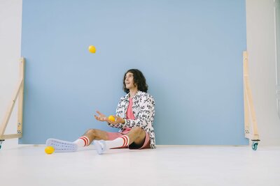 Man playing with balls while sitting down in front of photography backdrop