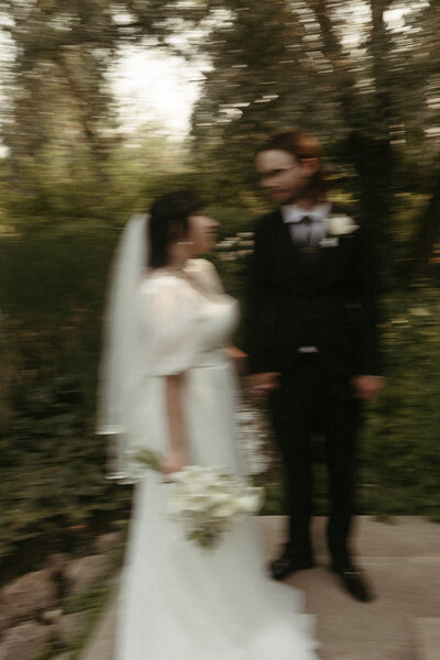 An artistic motion-blur photo of a bride and wedding party standing outside, focusing on the wedding bouquet.