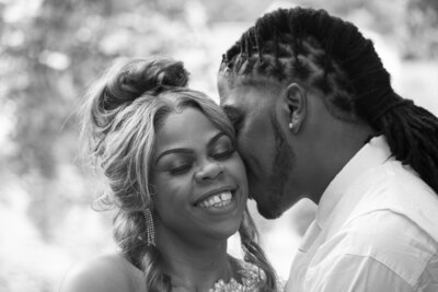 Bride smiling while being kissed by her groom