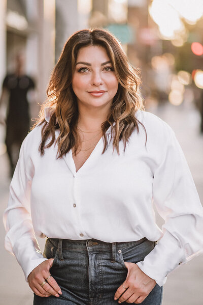 photo of woman on city sidewalk at sunset