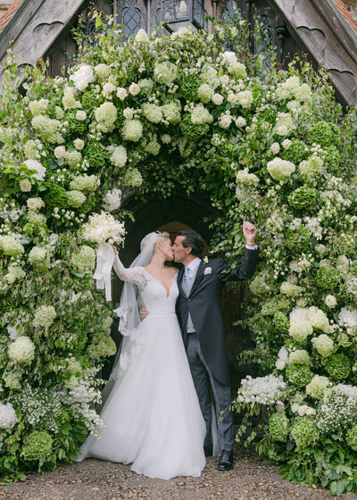 chloe-winstanley-weddings-hambleden-church-flower-arch-bride-groom-kiss