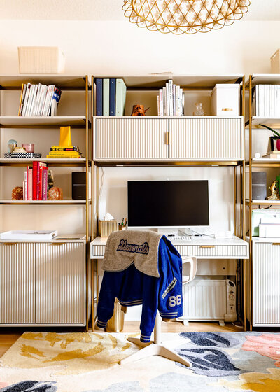 A home office featuring shelves and a computer desk along with colorful home decor and a bright floral rug.