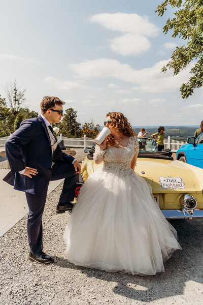 Bride and groom pose in front of vintage car