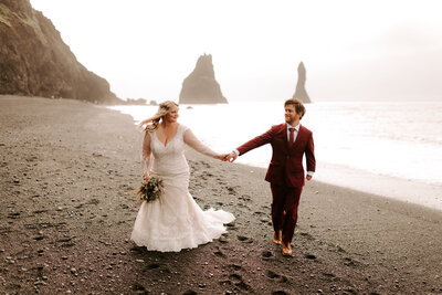 Bride and groom walk hand-in-hand down beach at an Elopement on the beach in Iceland