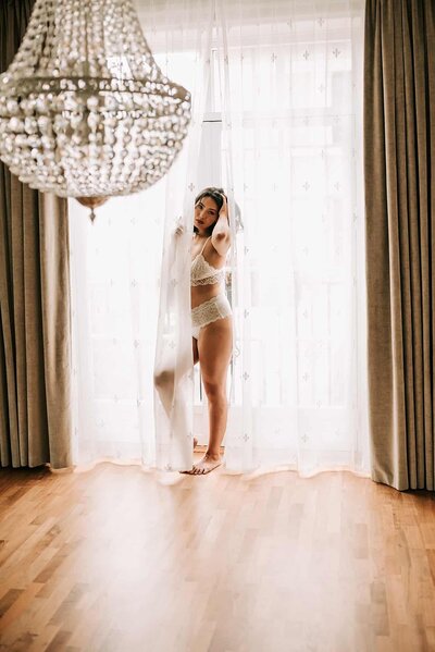 En kvinne i undertøy står i et stort rom under boudoirfotografering i Oslo.
