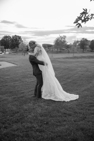 black and white photo of groom picking up bride