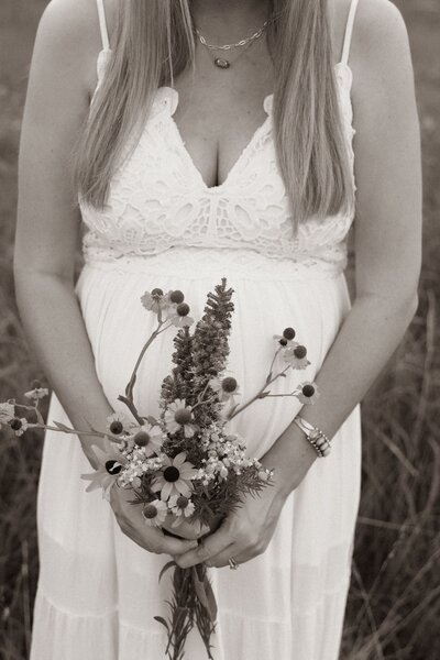 Black and white bouquet of wildflowers in front of pregnant belly
