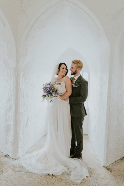 Bride and groom posing for portrait with white walls
