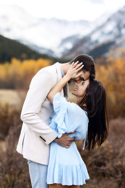 A beautiful couple posing in front of the mountains for their engagement photoshoot,