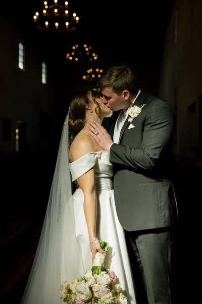 bride and groom hugging while leaning against limo