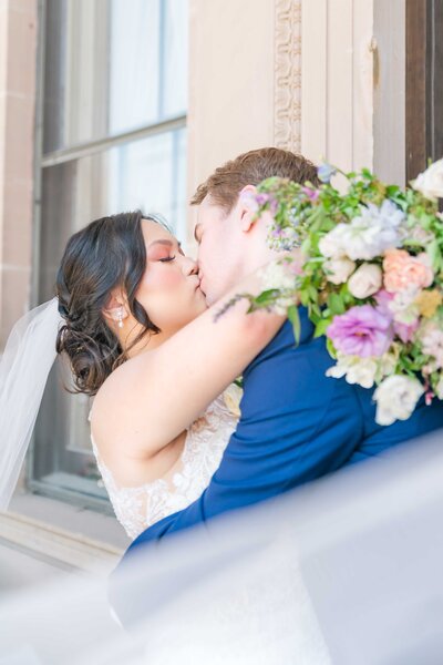 bride and groom hugging in front of doors of Historical Post Office in Ottawa Kansas