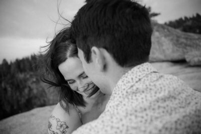 Windy couples photo session captures couple embracing atop Yosemite National Park at dusk.