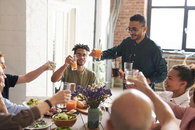 group of people lifting glasses to cheers at the dinner table