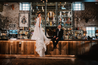 Groom lifting and kissing bride in front of a glamorous backlit bar at Wharfedale Grange wedding venue in Leeds, showcasing a luxury and romantic wedding moment.