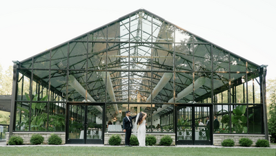 Bride and groom stand outside the conservatory at Evergreen in Indianapolis