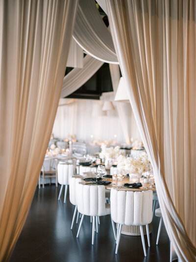 A beautifully decorated reception space featuring soft white drapery, elegant tablescapes, and modern decor.