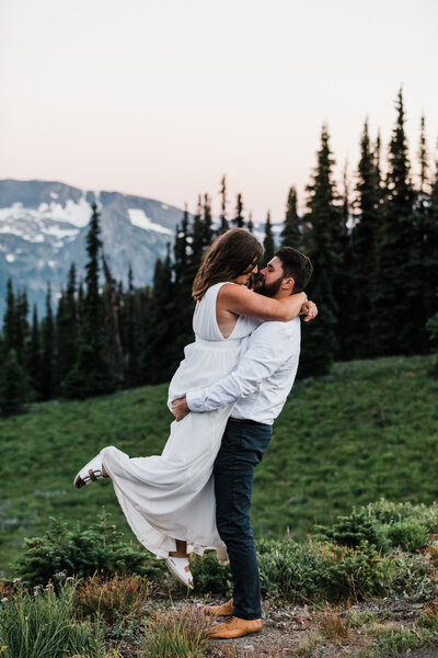 A groom lifts his bride up at their Mt Rainier National Park elopement in Washington.