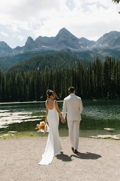 bride and groom walk away during their couples portraits at their fernie wedding