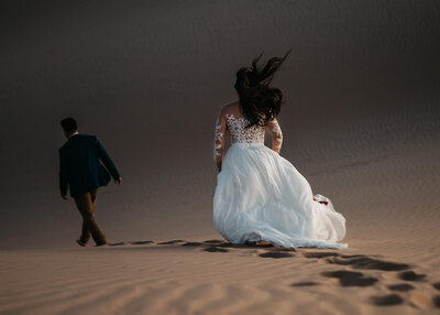 bride and groom running in the sand dunes - Colby and Valerie Photography