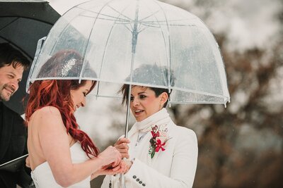 Wedding photo in Yosemite National Park of two brides under and umbrella during their wedding ceremony.