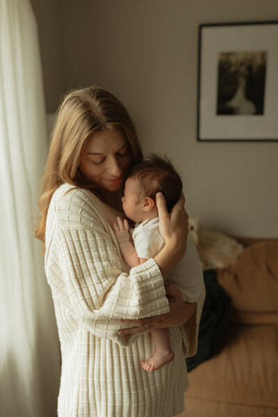 mom holding newborn during lifestyle photo session in pei