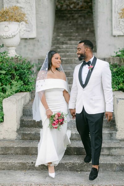 Elegant bride and groom holding hands on stone steps of a historic Italian villa — Destination Wedding Photographer Portfolio.
