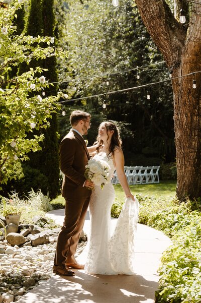 Bride and groom in a lit garden, bride holding her veil