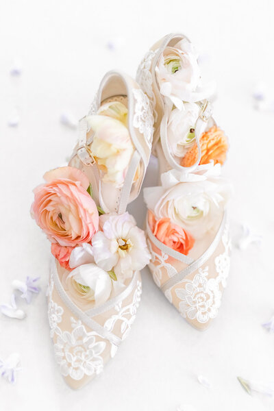 bright light and airy wedding photo of brides shoes details flowers flatlay