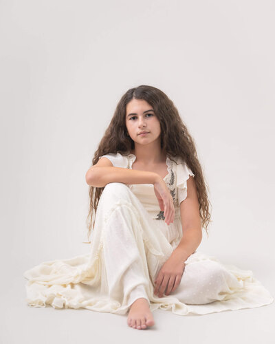 beautiful portrait of girl in cream sitting on floor in studio