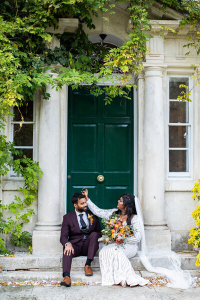 bride and groom sitting in front of green door