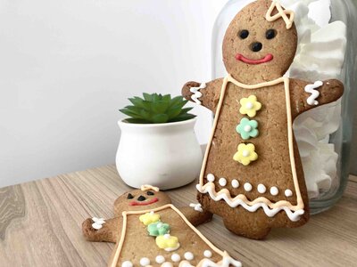 two gingerbread girls with a glass jar filled with white meringue rosettes.