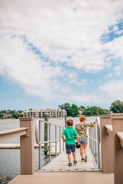 two young children running on a  floating dock in  Hampton Roads Virginia for family photos with the best family photographer in Newport News