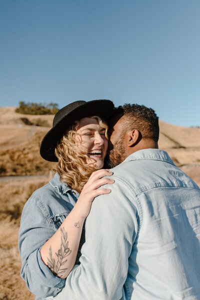 Couple smiling together while standing in the rolling hills of san jose