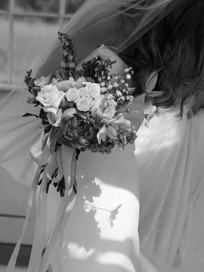 Black and white bridal portrait captured at Davis and Grey Farms in Texas. A timeless fine art wedding image featuring a bride holding a romantic bouquet with soft shadows and a flowing veil.