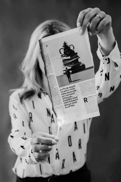 Black and white image of Sarah Klongerbo lighting a magazine page on fire with a match