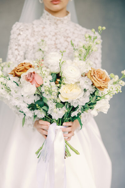 Close-up photo of a bride holding a  large bouquet of flowers