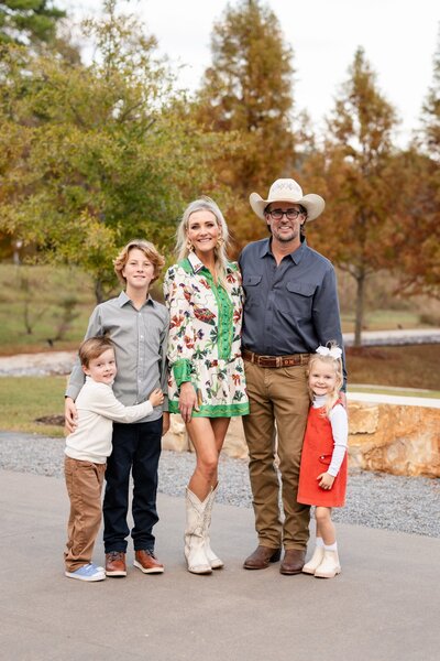 The full Munsey family posing outdoors in fall, with David and his wife standing behind their three children, smiling and dressed in coordinating outfits.
