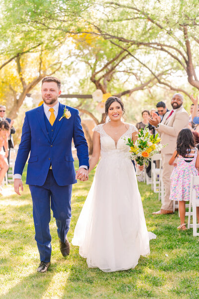 bride and groom leaving ceremony holding hands