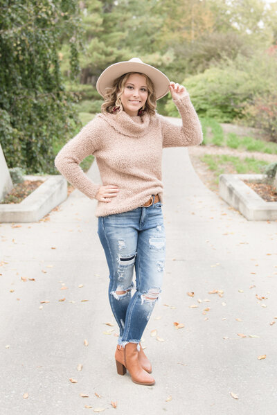 senior girl standing at Dow Garden with one hand on hip and one on her hip
