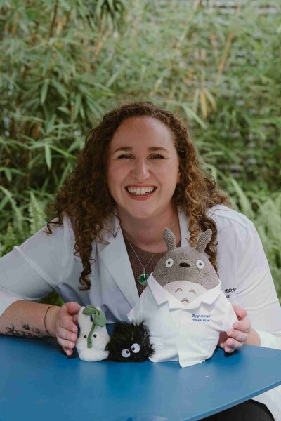 Christy Walowit, a US nutrition counselor, smiles while holding a stuffed animal in her lab coat.