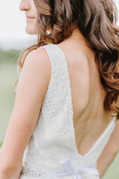 bride looking away wearing an open back dress with loose curls in hair
