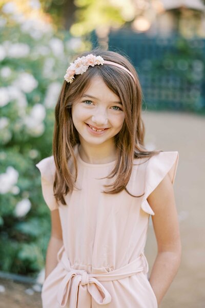 young girl with her hands in her pockets and smiling at the camera