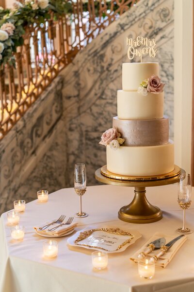 Elegant four-tier wedding cake with gold accents and blush florals at Omni Severin Hotel reception in downtown Indianapolis