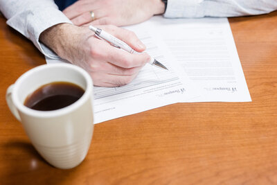 Bethany filling out paperwork next to a mug of coffee