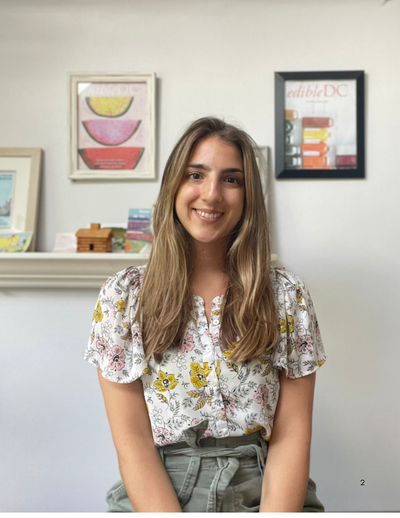 Emma Newell smiling, wearing a white blouse with flowers