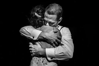 A groom tightly embraces his bride