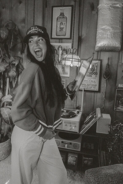A girl with a hat on posing for the camera with her hands on her hips