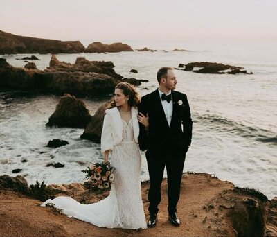 Couple in elegant wedding attire standing on the cliffs near Alila Ventana Big Sur