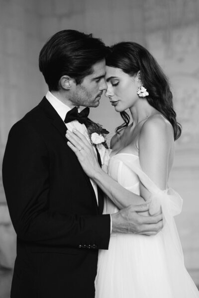 A candid black and white image of a wedding couple gently embracing in a private moment after their wedding ceremony at Chateau Jalesnes