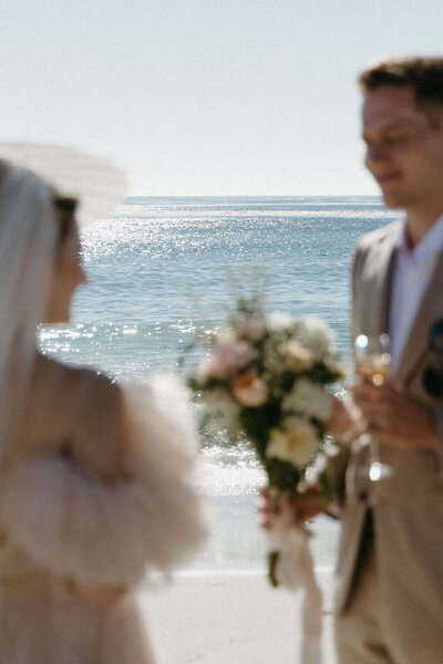 Carmel CA Elopement. Couple in wedding attire stand in front of ocean in Carmel CA